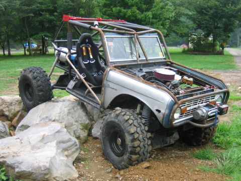 1992 Ford Mustang - This heavily modified vehicle, likely a custom buggy, is positioned on a rocky terrain, a prominent roll cage and a winch.