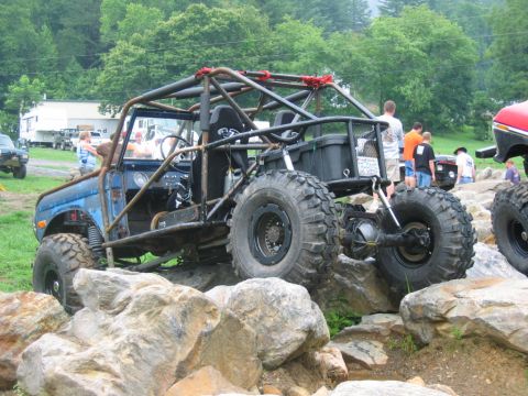 1992 Ford Mustang - This heavily modified off-road vehicle navigates a rocky terrain, with spectators visible in the background.