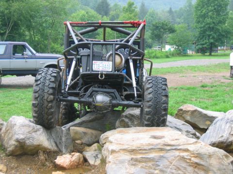 1992 Ford Mustang - A custom-built buggy navigates a rocky obstacle course, with another vehicle parked nearby.