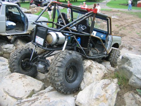 1992 Ford Mustang - A heavily modified off-road vehicle is shown traversing a rocky terrain, with another vehicle partially visible.