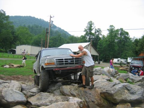 1992 Ford Mustang - A man poses with a lifted Ford Bronco navigating a rocky terrain.