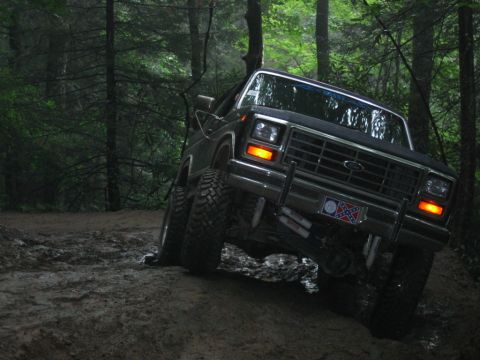 1992 Ford Mustang - This Ford F-Series truck navigates a muddy off-road path through a forest.