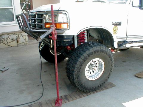 1996 Ford Bronco - The front bumper of a 1996 Ford Bronco is shown with a jack positioned to lift the front wheel.