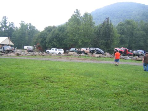 1979 Ford Bronco - Multiple off-road vehicles are staged on a rocky area with a wooded hillside in the background.