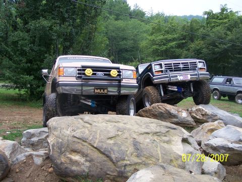 1979 Ford F-150 - Two lifted Ford Broncos navigate a rocky obstacle course on a summer day.