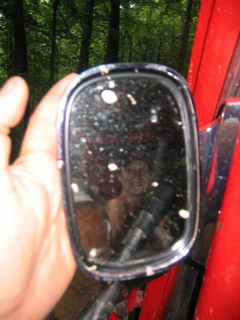 1979 Ford Bronco - A person smiles from inside a red vehicle, reflected in the side mirror.
