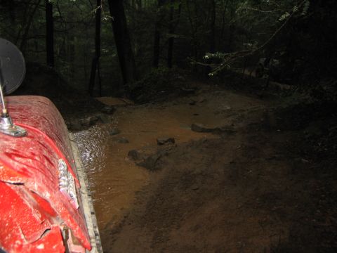 1979 Ford Bronco - Driving a red vehicle through a muddy trail in a forest.