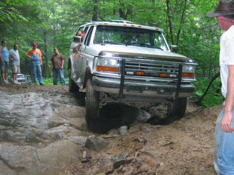 1992 Ford Mustang - White Ford Bronco tackling a challenging off-road course in a wooded area.
