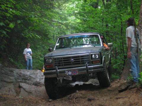 1992 Ford Mustang - A Ford truck navigates a rocky, wooded trail with two onlookers.