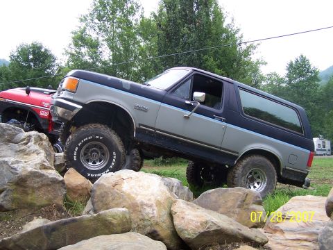 1979 Ford F-150 - A lifted Ford Bronco navigates a rocky obstacle course, with another off-road vehicle nearby.
