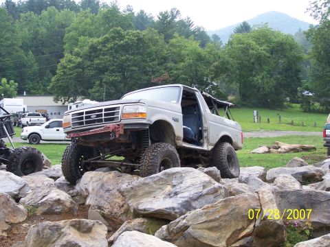 1979 Ford F-150 - A heavily modified truck navigates a rocky terrain, with other vehicles visible in the background.