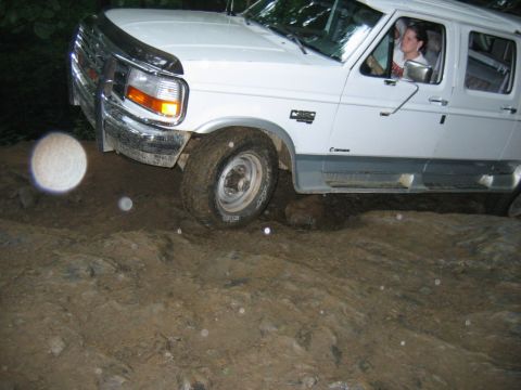 1992 Ford Mustang - A white Ford F-Series truck is shown off-roading over rocks and mud.