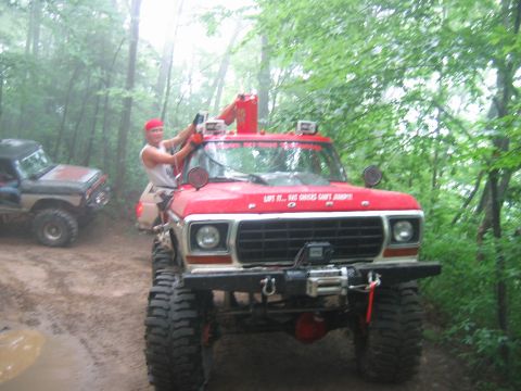 1992 Ford Mustang - Modified red Ford pickup truck with a man on top, driving off-road with another vehicle.