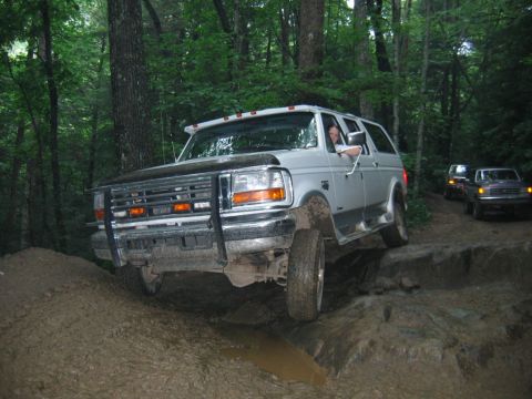 1992 Ford Mustang - A Ford Bronco tackles a challenging off-road course in a wooded area.