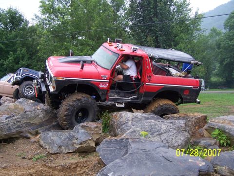 1979 Ford F-150 - Modified red Ford Bronco navigating a rocky trail with other off-road vehicles present.
