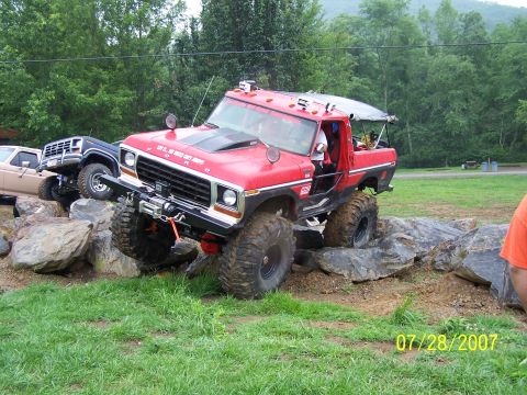 1979 Ford F-150 - Modified Ford pickup truck tackles a rocky obstacle course with other vehicles nearby.