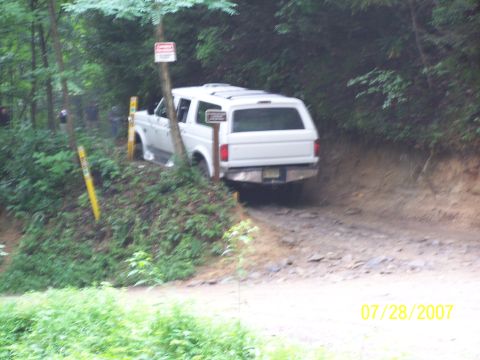 1979 Ford F-150 - A white SUV navigates a rough dirt road surrounded by trees, with a date stamp indicating July 28, 2007.