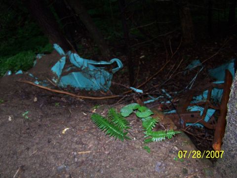 1979 Ford F-150 - Wrecked turquoise car body is visible in a wooded area, covered in dirt and debris.