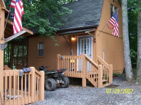 1979 Ford F-150 - An ATV is parked beside a rustic cabin, with American flags displayed prominently.