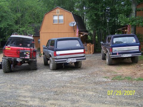 1979 Ford F-150 - Three Ford Broncos are parked in a gravel driveway with a wooden barn in the background.