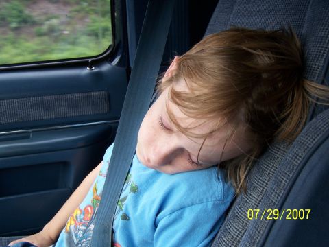 1979 Ford F-150 - A young child sleeps soundly while buckled into a car seat during a journey.
