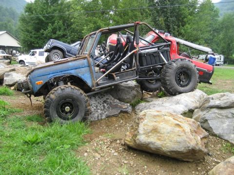 1995 Ford Bronco - Custom off-road buggy navigating a rocky obstacle course with other vehicles nearby.