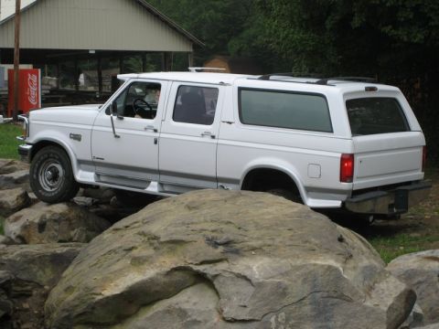 1995 Ford Bronco - A white SUV navigates a rocky terrain, its body style suggesting a model year around 1992.