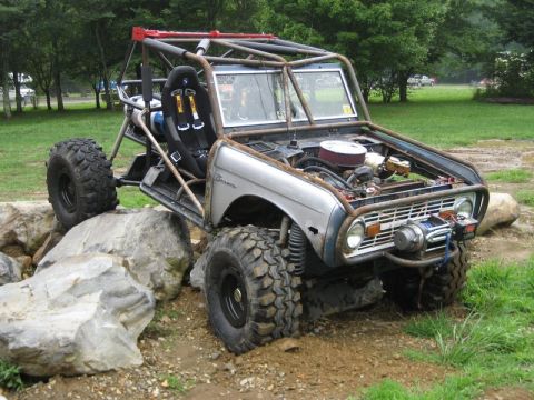 1995 Ford Bronco - Customized early Bronco buggy with roll cage and winch navigating a rocky obstacle course.
