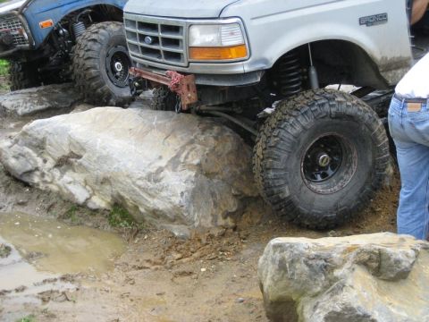 1995 Ford Bronco - A silver Ford Bronco is shown navigating a rocky off-road trail, with another vehicle partially visible.
