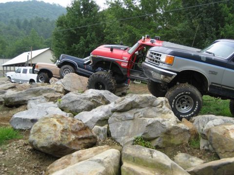 1995 Ford Bronco - Several modified trucks are positioned on a challenging rocky obstacle course.