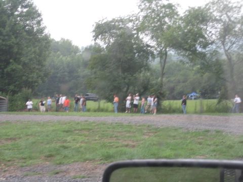 1995 Ford Bronco - People gathered outdoors with a dark SUV in the background on a cloudy day.