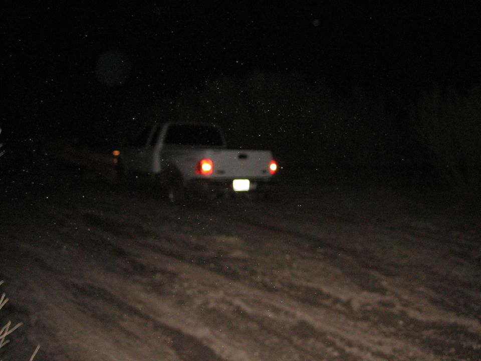 White pickup truck rear view at night on dirt road