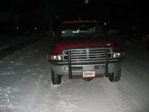 1996 Dodge 2500 - A red Dodge pickup truck sits in the snow at night, its front grille and headlights illuminated.