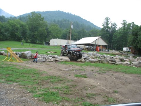 1995 Ford C-350 (Centurion Conversions) - Off-road vehicle maneuvers through a challenging rocky terrain course on a cloudy day.