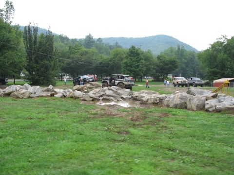 1995 Ford C-350 (Centurion Conversions) - Several off-road vehicles are seen maneuvering through a challenging rocky terrain with spectators watching the event.