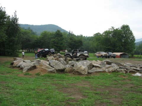 1995 Ford C-350 (Centurion Conversions) - Multiple off-road vehicles are seen navigating a challenging rock obstacle course in a rural setting.