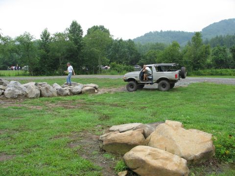 1995 Ford C-350 (Centurion Conversions) - A gray Ford Bronco is parked on a dirt and grass area with a person inside and another person walking nearby.