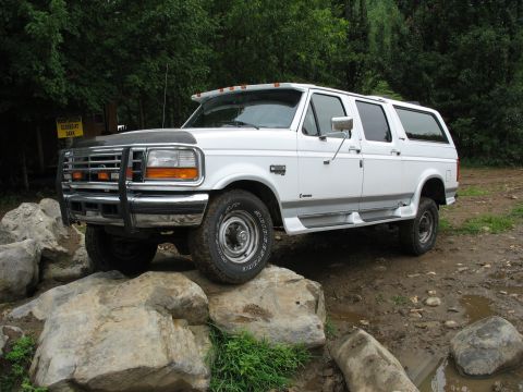 1995 Ford C-350 (Centurion Conversions) - White 1995 Ford C-350 (Centurion Conversions) positioned on large rocks in a wooded area.