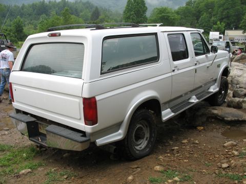 1995 Ford C-350 (Centurion Conversions) - White SUV with a camper shell navigates a rocky path off-road.