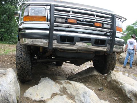 1995 Ford C-350 (Centurion Conversions) - Front view of a 1995 Ford C-350 (Centurion Conversions) with a brush guard, driving over rocks.