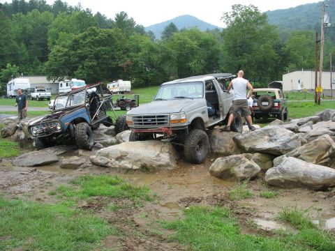 1995 Ford C-350 (Centurion Conversions) - A modified Ford Bronco tackles a rocky obstacle course with a second Bronco visible in the background.