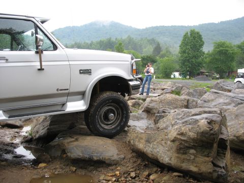 1995 Ford C-350 (Centurion Conversions) - A white Ford F-Series truck navigates a rocky terrain, with a person observing and taking pictures.