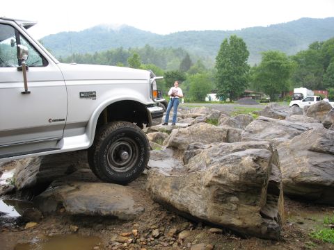 1995 Ford C-350 (Centurion Conversions) - White Ford F-Series truck navigates a rocky terrain, with another truck and RV in the background.