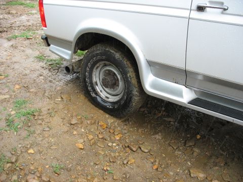 1995 Ford C-350 (Centurion Conversions) - The van's tire is on a muddy road with water splashing.