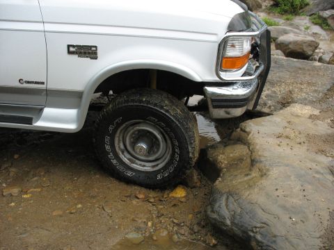 1995 Ford C-350 (Centurion Conversions) - A white Ford F-350 Classic truck navigates rocky terrain with its front wheel turned.