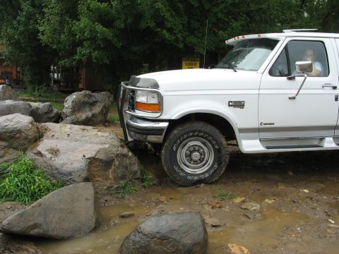 1995 Ford C-350 (Centurion Conversions) - White Ford F-250 truck navigates a rocky, muddy terrain.