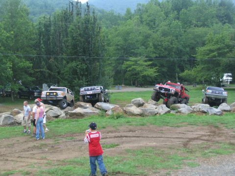 1995 Ford C-350 (Centurion Conversions) - Modified trucks tackle a challenging rock obstacle course with spectators watching.