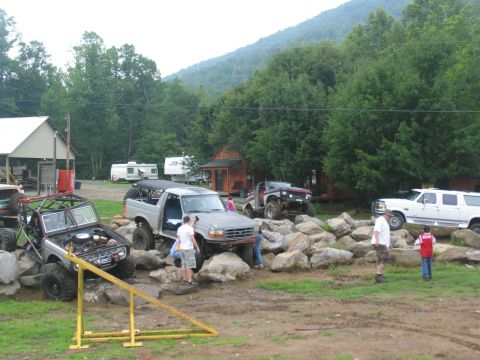 1995 Ford C-350 (Centurion Conversions) - Silver Ford Bronco with aftermarket roll cage is positioned on rocks, with its hood open.