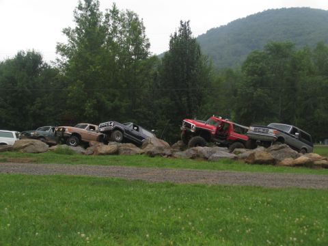 1995 Ford C-350 (Centurion Conversions) - Multiple trucks are navigating a rocky obstacle course in a rural setting.