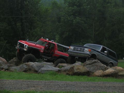 1995 Ford C-350 (Centurion Conversions) - Two modified trucks navigate a rocky obstacle course, one appears to be towing the other.